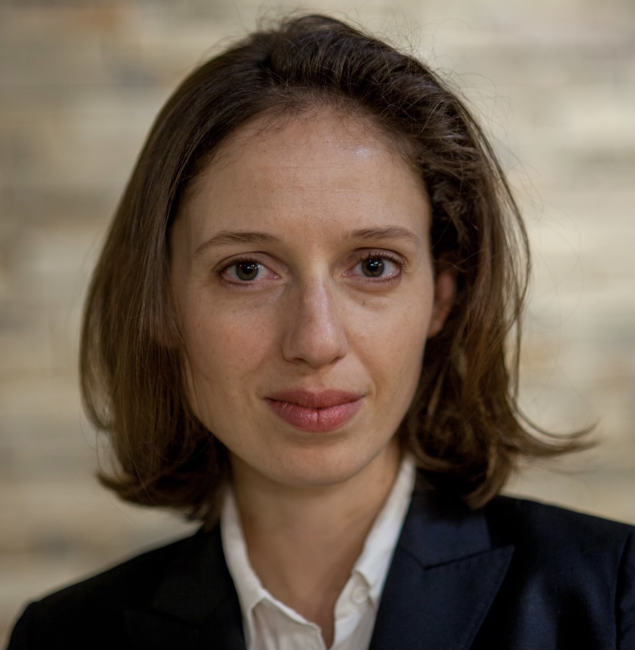 Headshot of a woman with shoulder-length hair in a black suit jacket and white shirt