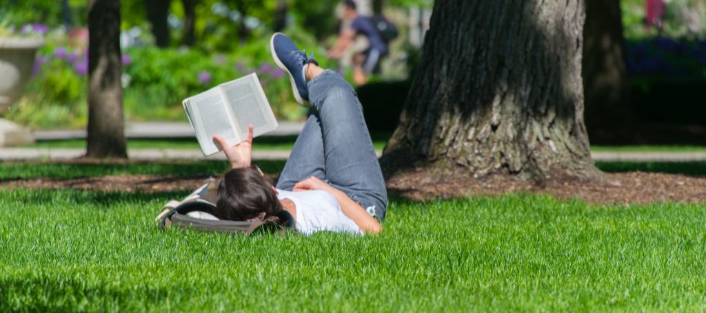 girl laying in the grass on the quad